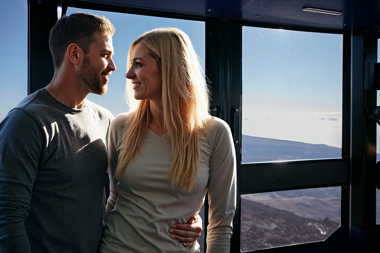 Couple watching through the glass of the Cable Car as it ascends in exclusive groups to watch the sunset